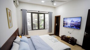 Moderni hotellihuone, jossa on suuri sänky, televisio ja ikkuna, jossa on verhot.