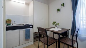 A compact kitchen with a sink, cabinets, and a dining area with two chairs and a table.