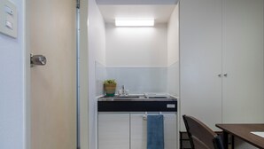 A compact kitchen with a sink, a small countertop, and a cabinet with a towel hanging.