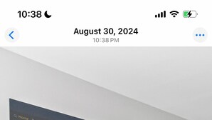 Un salon moderne avec un téléviseur fixé au mur diffusant une publicité de Bosch, une console noire avec une horloge et une plante en pot.