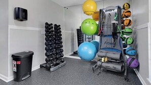 Une salle de sport équipée d’haltères, de ballons d’exercice et d’un appareil de musculation.