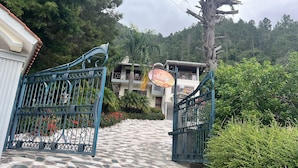 A gated entrance to a building with a stone-paved path leading to a balcony with a view of a forested area. - Summit LuxeVilla (Constanza)