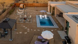 Un jardin avec une piscine, un espace salon extérieur et un sauna.