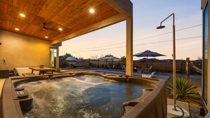 Un bain à remous doté d’un plafond en bois et offrant une vue sur un espace patio aménagé avec du mobilier d’extérieur.