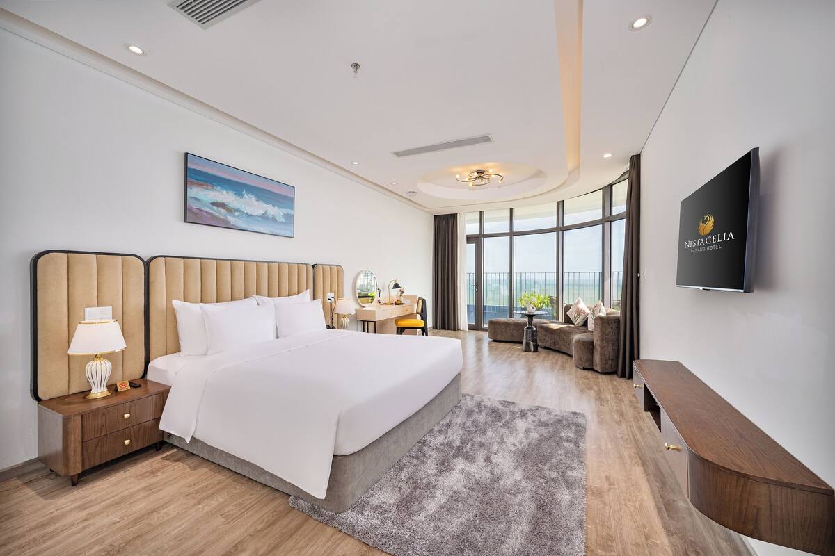 Een moderne hotelkamer met een groot bed, een bureau, een televisie en uitzicht op de stad.