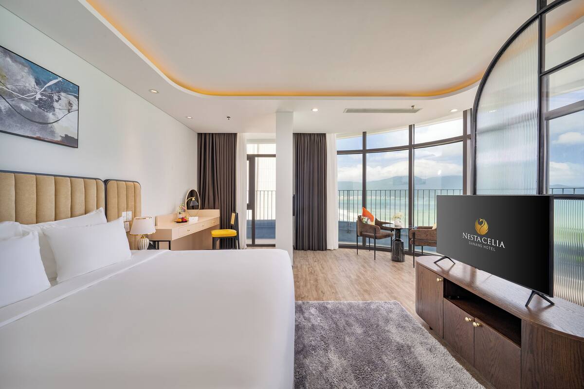 Een hotelkamer met een groot bed, een bureau, een televisie en uitzicht op de bergen.