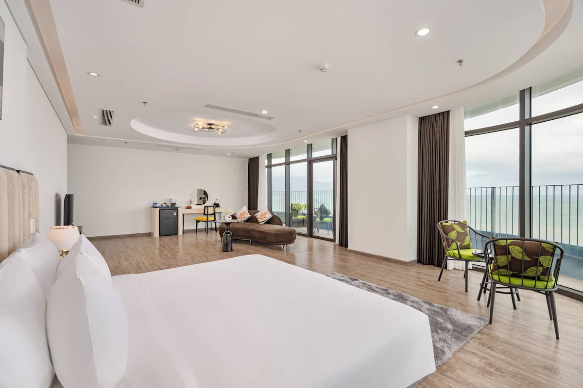 Een moderne hotelkamer met een groot bed, een bureau, twee stoelen en een balkon met uitzicht.