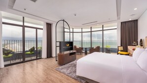 Ein modernes Hotelzimmer mit einem großen Bett, einem Fernseher, einem Balkon mit Sitzgelegenheiten und Blick auf die Stadt.