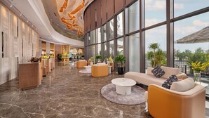 Eine geräumige Lobby mit Marmorboden, modernen Sitzgelegenheiten und großen Fenstern mit Blick ins Freie.