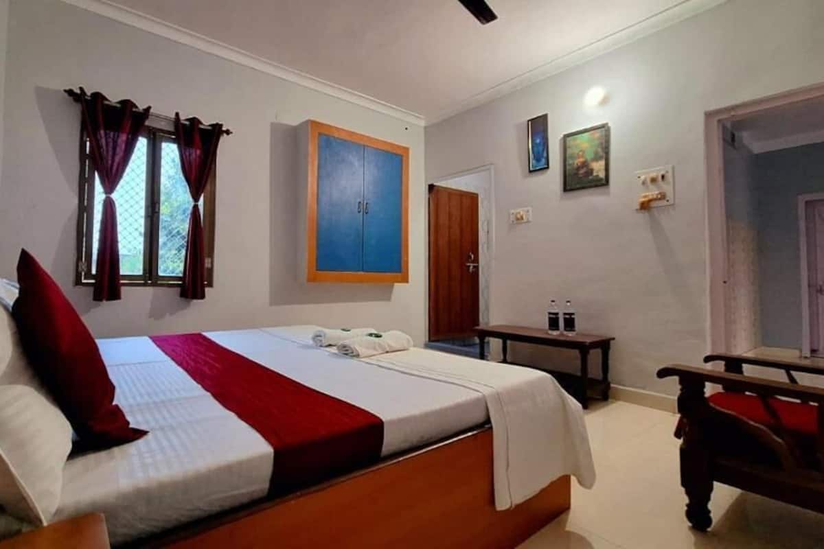 A bedroom with a bed, a wardrobe, a desk, and a chair.