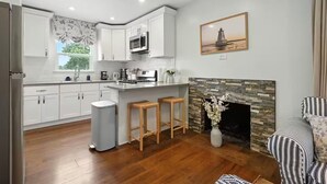 Een moderne keuken met witte kasten, een centraal eiland en een stenen open haard.