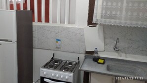 A kitchen with a white refrigerator, a gas stove, and a sink.