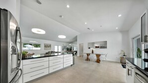 A modern kitchen with white cabinetry, stainless steel appliances, and a central island with seating. - Luxury Villa Serena Heated Pool 15 min to Beach (Miami)