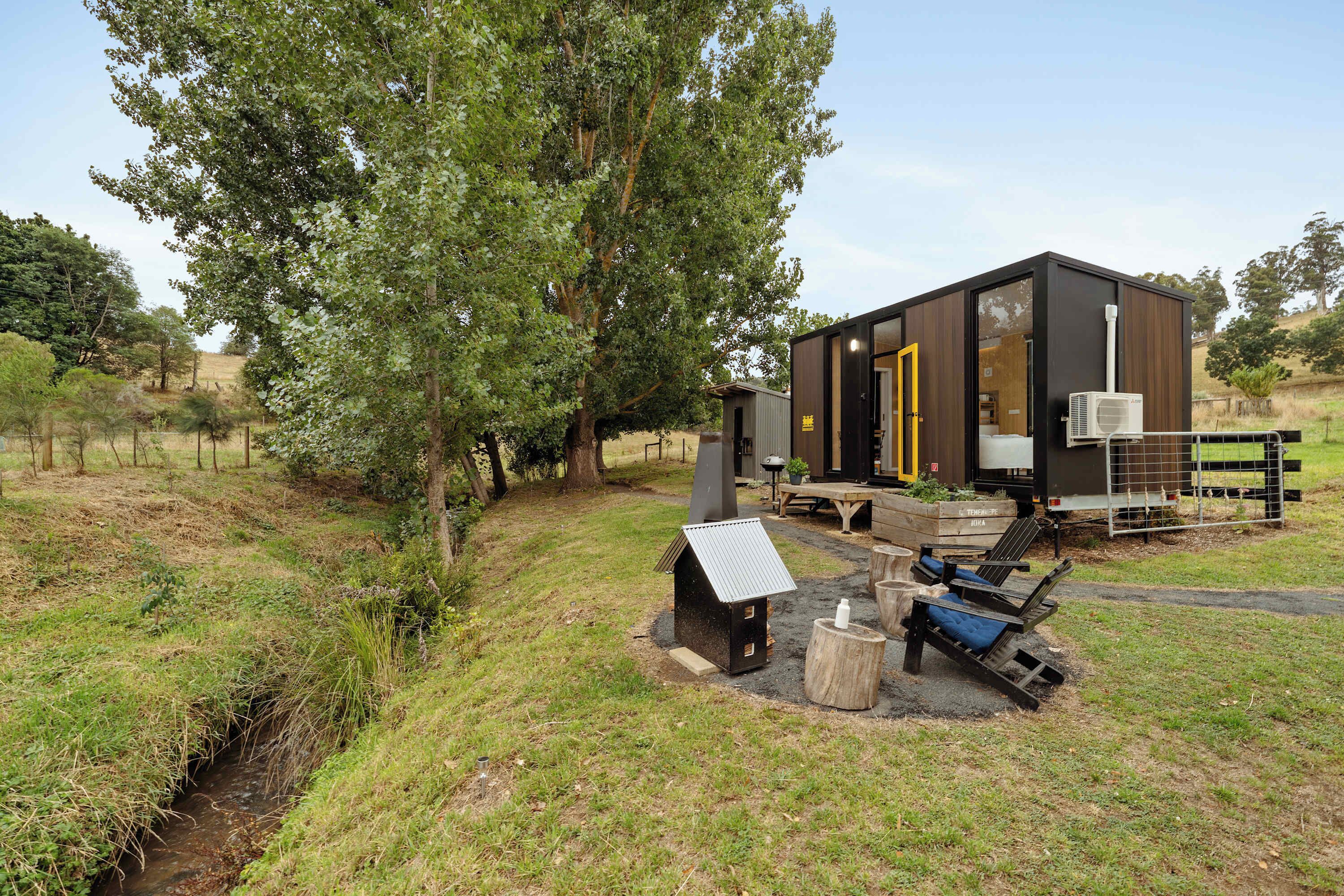 A modern cabin with a wooden exterior, a small porch, and a solar panel.