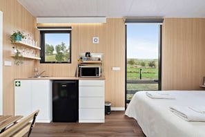 Une chambre moderne dotée d’un coin cuisine, d’un lit et d’une fenêtre donnant sur l’extérieur.
