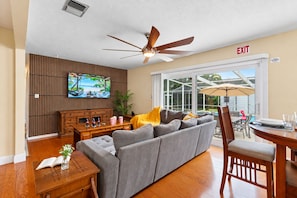 A living room with a grey sofa, wooden coffee table, and a TV mounted on a wall.