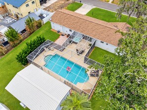 A residential property with a swimming pool, fenced patio area, and a detached garage.