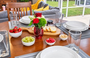 Een eettafel gedekt met borden, glazen en schalen met fruit.