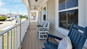 A covered porch with a white railing, a blue bench, and a white rocking chair.