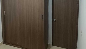 Two wooden wardrobes in a room with a tiled floor and a white wall.
