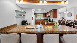 Una cocina moderna con encimeras de granito, gabinetes de madera y una isla central con asientos.
