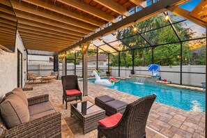 Un espacio al aire libre techado con piscina, sillas de descanso y una canasta de baloncesto.