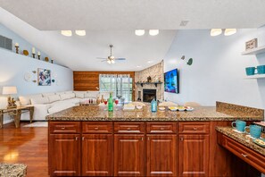 Una cocina moderna con una isla central, armarios de madera y un área de comedor con sofá.