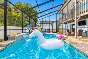Ein Schwimmbecken mit einem Einhorn-Schwimmpfiff, einer Wasserfallanlage und Gartenmöbeln.