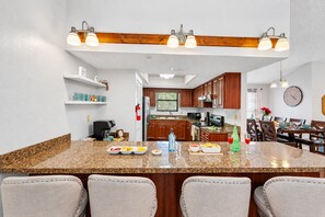 Una cocina con encimeras de granito, armarios de madera y un comedor con sillas y una mesa.