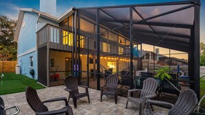 Un porche cubierto con mobiliario exterior y vista a una casa.