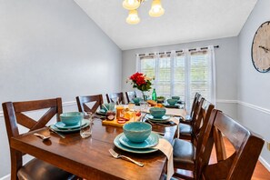 Comedor con mesa de madera dispuesta para seis personas, rodeado de sillas.