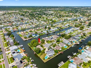 A residential area with houses arranged in rows along a canal, featuring green lawns and small docks.