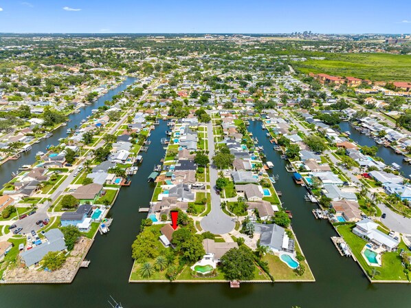 A marina with numerous boats docked, surrounded by residential buildings with visible swimming pools and green lawns.