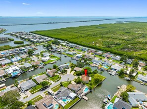 An aerial view of a coastal residential area with houses, boats, and a marina.