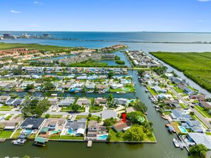An aerial view of a coastal residential area with houses, a marina, and a large body of water.