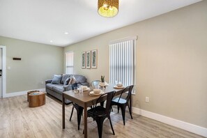 Un coin repas avec une table en bois, des chaises noires et un canapé gris.