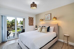 A bedroom with a large bed, a view to the outside, and a small table by the window.