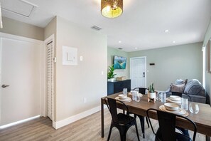 A dining area with a wooden table set for four, surrounded by black chairs.