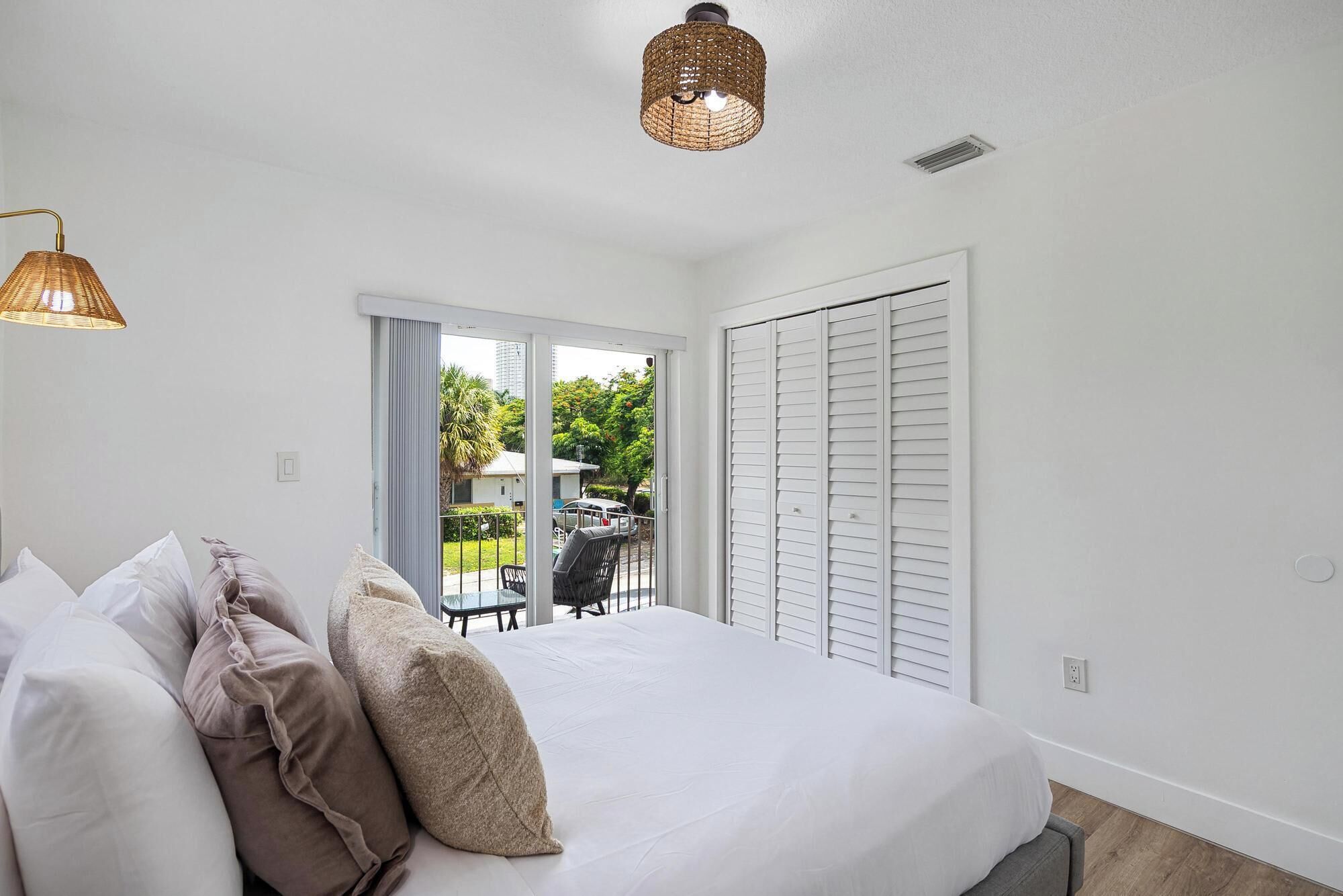 Une chambre à coucher avec un lit, des oreillers, un balcon avec vue et un luminaire au plafond.