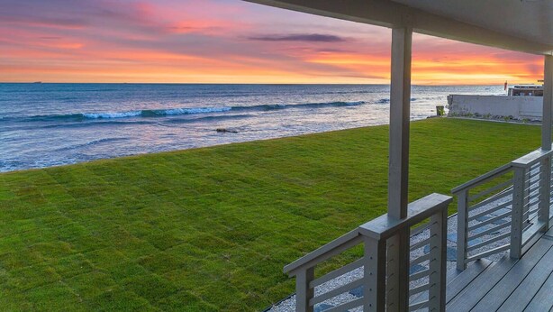 A balcony with a view of the ocean at sunset.