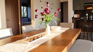 Une table à manger ornée d’un vase de fleurs, d’une assiette de nourriture et d’une horloge au mur.