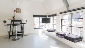 A bright room with a large window, a flat-screen TV, and a small table with chairs. - Laurier Apartment - in the Jordaan (Amsterdam)