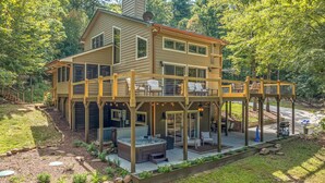 A two-story house with a covered patio area, outdoor seating, and a hot tub.