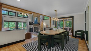 A modern dining area with a round table, green upholstered chairs, and a black and white striped rug.