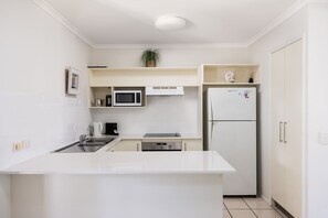A compact kitchen with a white countertop, a microwave, a refrigerator, and a sink. - Riverside Rest on Noosa River (Noosa)