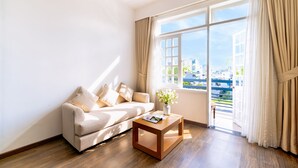A modern living room with a sofa, a coffee table, and a window with curtains. - Sujet Beach Hotel &Apartment by Haviland (Da Nang)
