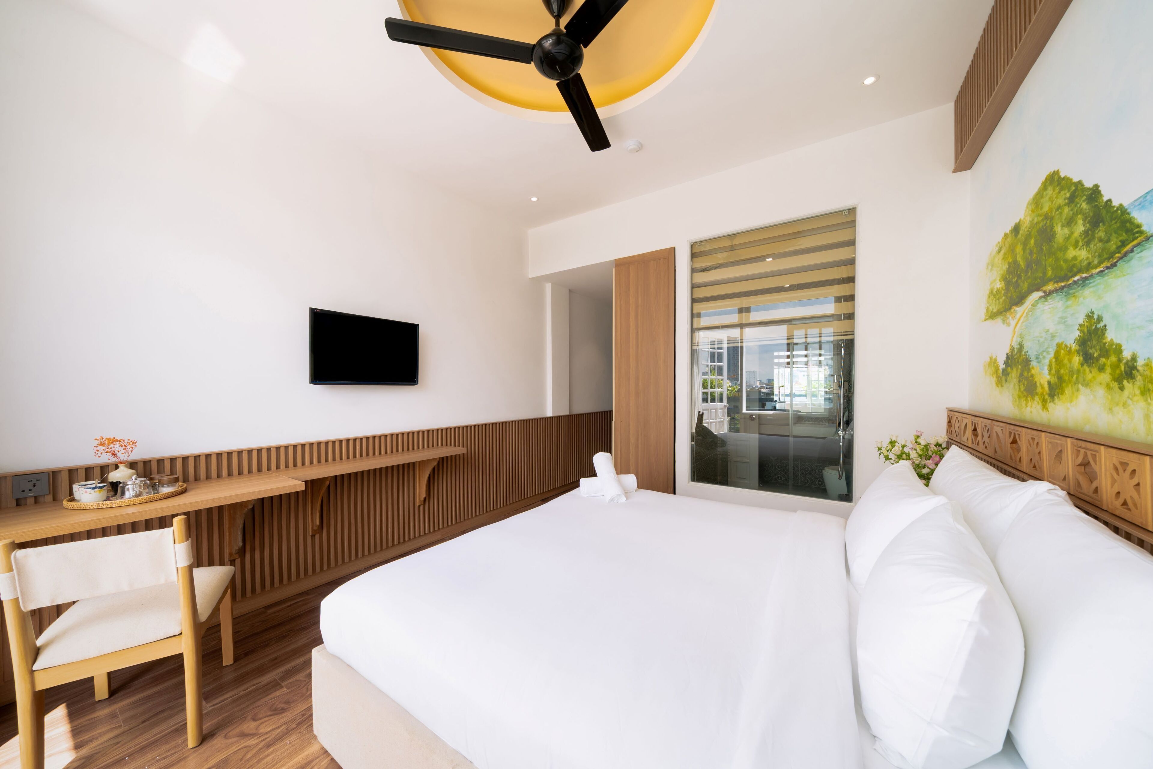 Habitación de hotel moderna con una cama grande, un escritorio de madera, un televisor de pantalla plana y vistas a la ciudad a través de la ventana.