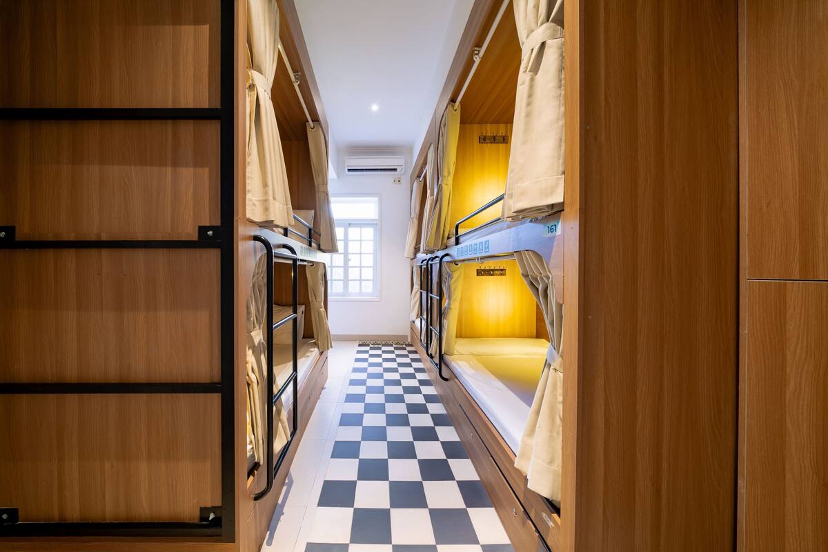 A corridor with bunk beds, wooden walls, and a checkered floor.