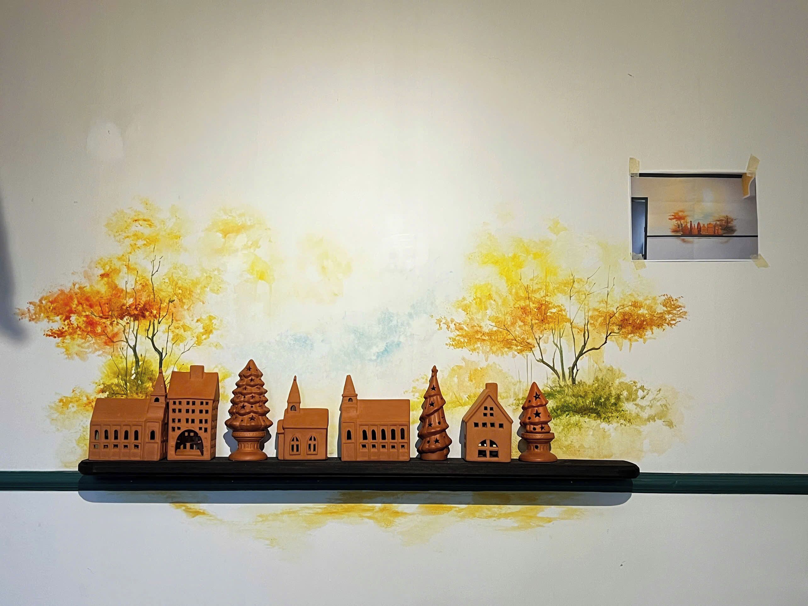 Une maquette représentant des bâtiments et des arbres, exposée sur une étagère le long d’un mur.