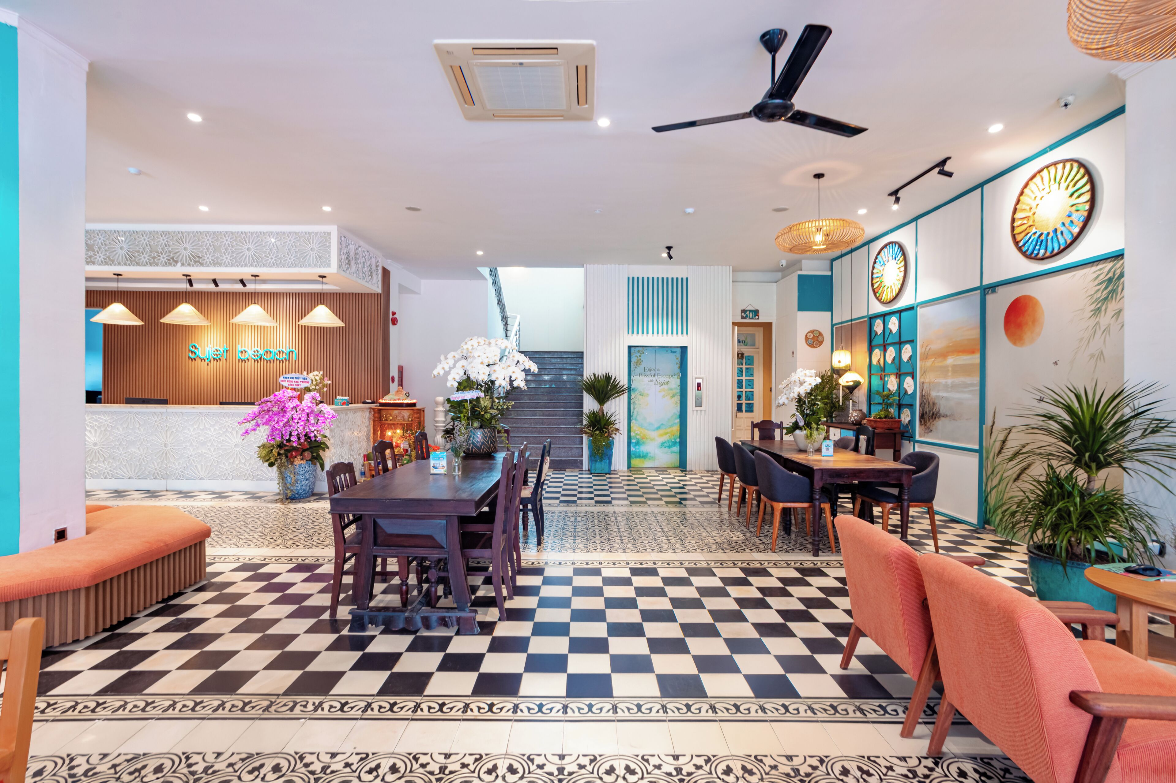 Eine Hotelhalle mit Schachbrettmuster-Boden, einer Rezeption und einer Treppe, die zu den oberen Stockwerken führt.